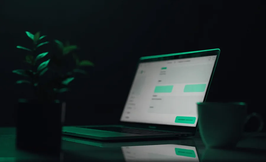 A laptop on a dark studio surface showing a website layout in Retiar green
